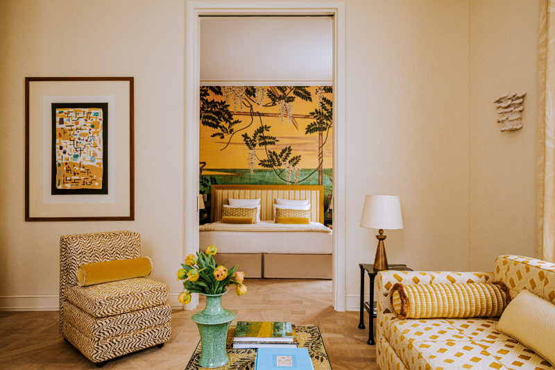 Laura Gonzalez Upholstery- Saint James suite. Here we see a bed, a sofa and an arm chair, yellow toned , we also have a center table with a green vase on top.