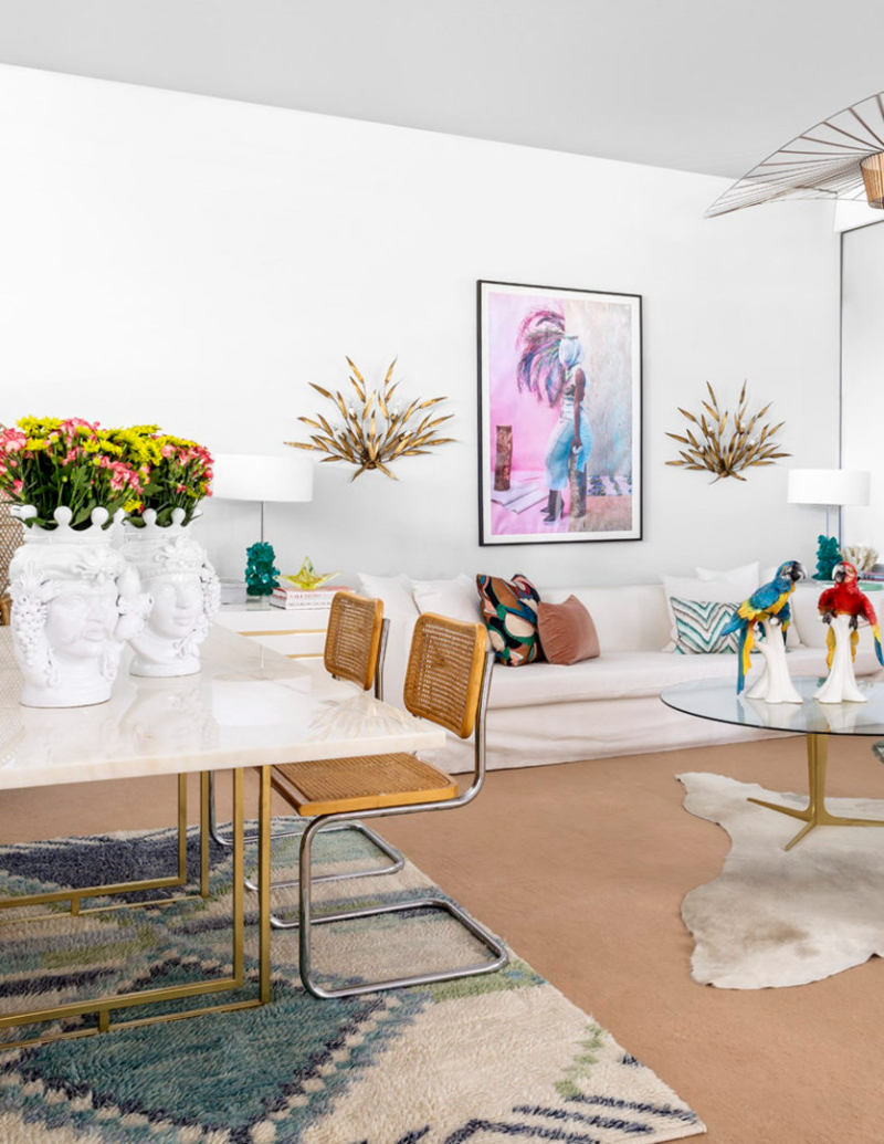 living room by Patricia Bustos Studio with white sofa, white dining table and colorful decorations